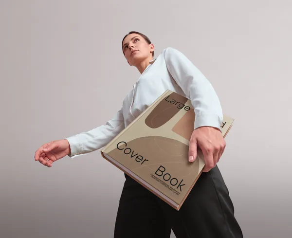 Low-Angle Professional Woman with Large Hard Cover Book Mockup PSD
